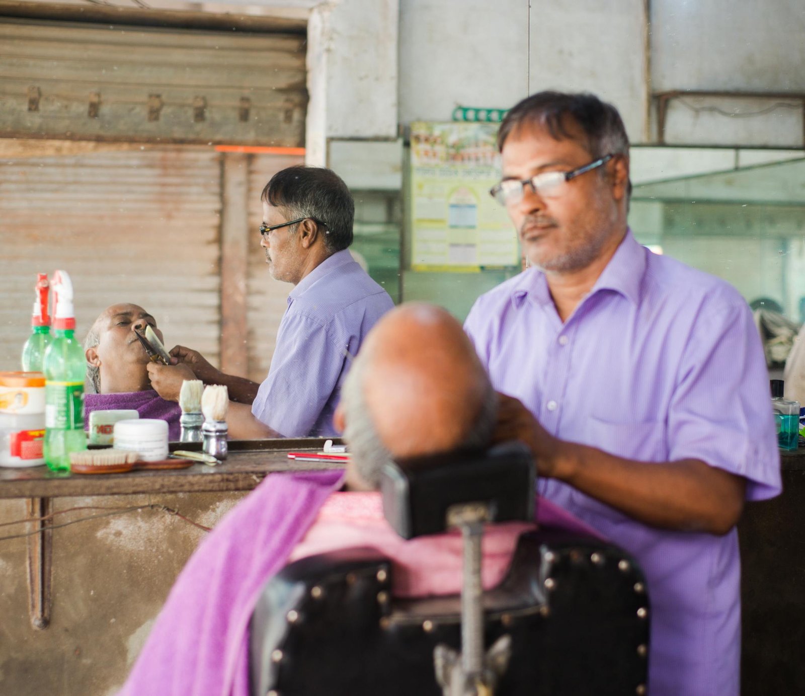 A barber performs a traditional shave on a customer in a classic barber shop setting, focusing on precision and care.